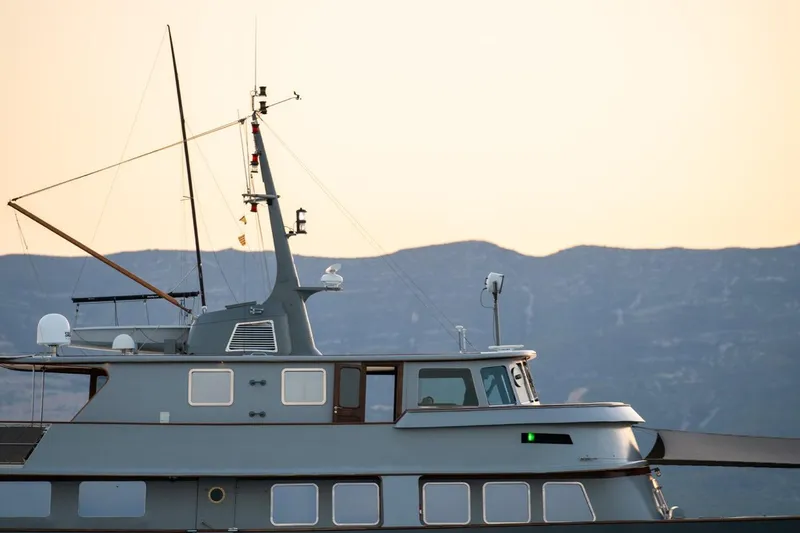 La Fenice Yacht Photos Pics 1962 Laurent Giles TSDMY Gentleman's Motor Yacht against a mountainous backdrop at sunset.