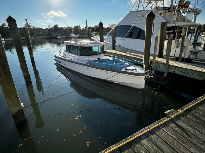 Lemaire Yacht Photos Pics 2023 Axopar 28 CABIN boat docked in a marina under clear skies.