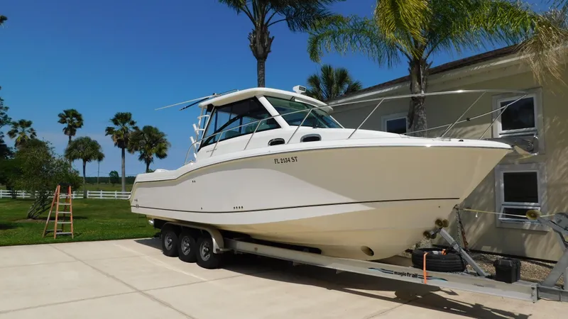  Yacht Photos Pics 2017 Boston Whaler 315 Conquest boat on trailer, parked near palm trees.