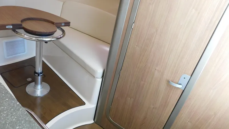  Yacht Photos Pics 2017 Boston Whaler 315 Conquest cabin interior with seating and wooden table.