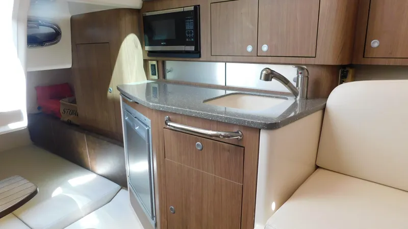  Yacht Photos Pics 2017 Boston Whaler 315 Conquest interior with kitchenette, featuring wood cabinets and modern appliances.