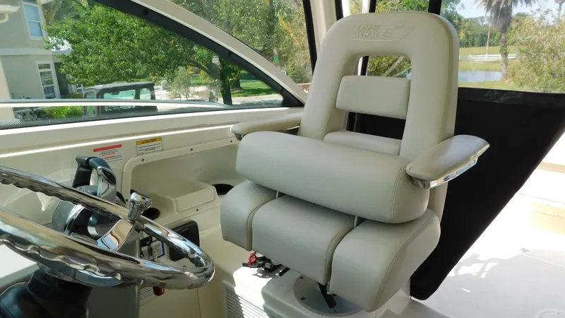  Yacht Photos Pics Captain's chair in 2017 Boston Whaler 315 Conquest boat cockpit, featuring steering wheel and controls.