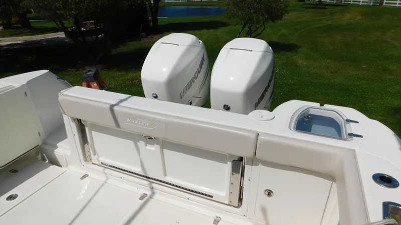  Yacht Photos Pics 2017 Boston Whaler 315 Conquest boat with dual outboard engines, docked on grassy area.