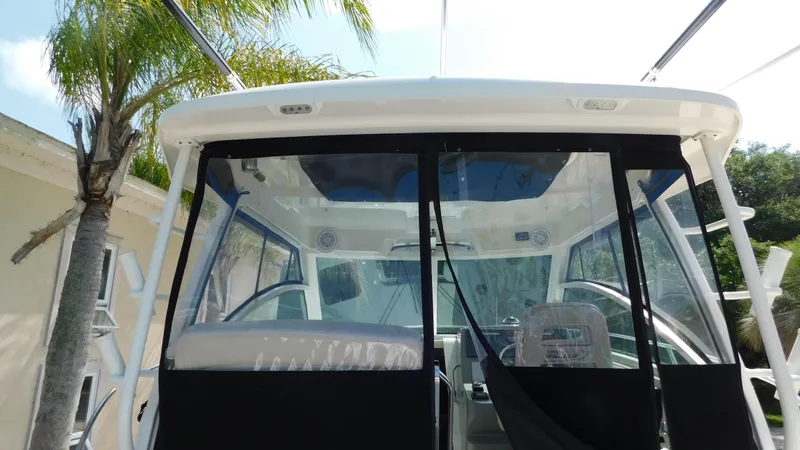  Yacht Photos Pics 2017 Boston Whaler 315 Conquest boat cockpit with clear enclosure and palm tree in background.