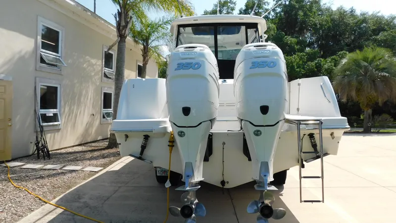  Yacht Photos Pics 2017 Boston Whaler 315 Conquest with twin outboard engines, parked on a sunny driveway.