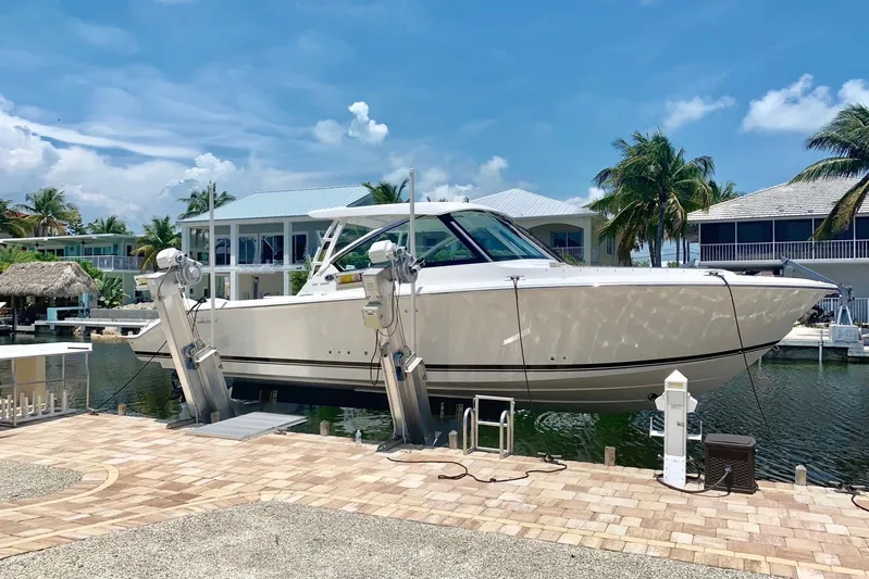 Perfect Draw Yacht Photos Pics 2020 Pursit DC 325 boat docked at a marina with palm trees and blue sky.