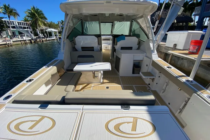 Perfect Draw Yacht Photos Pics 2020 Pursit DC 325 boat interior with seating and table, docked by waterfront homes.