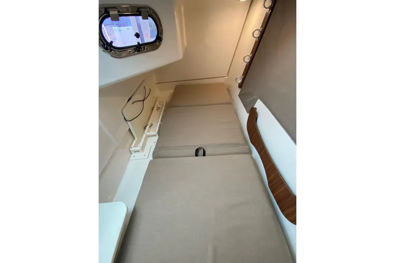 Perfect Draw Yacht Photos Pics Interior cabin of 2020 Pursit DC 325 boat, featuring beige cushions and porthole window.