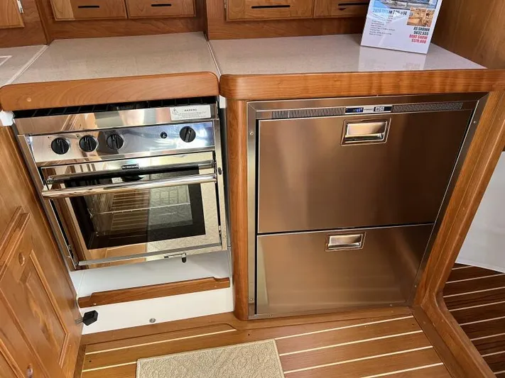 #14 Yacht Photos Pics Modern kitchen in 2024 Tartan 395 yacht with stainless steel appliances and wooden cabinetry.