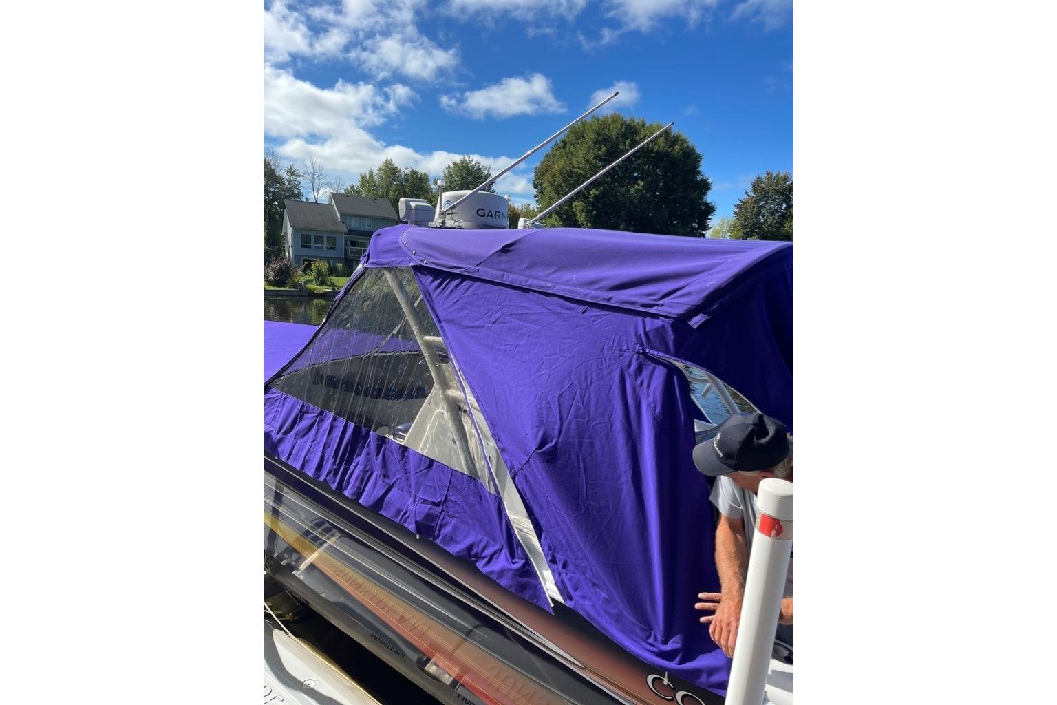 2014 Concept Boats 36CC with purple cover, docked under a clear blue sky.