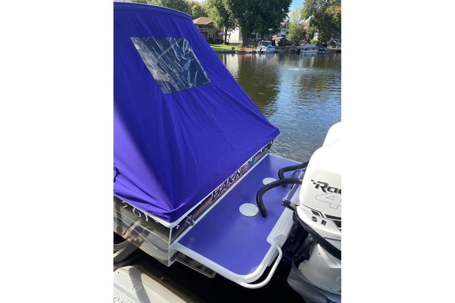 2014 Concept Boats 36CC with purple cover and outboard motor on a calm lake.