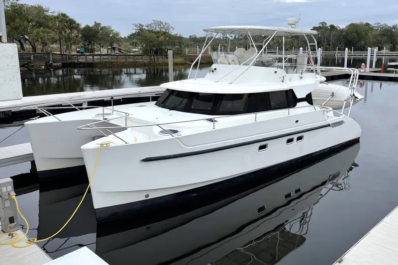 Imagine Yacht Photos Pics 2000 Fountaine Pajot Maryland 37 catamaran docked at a marina, reflecting on calm water.