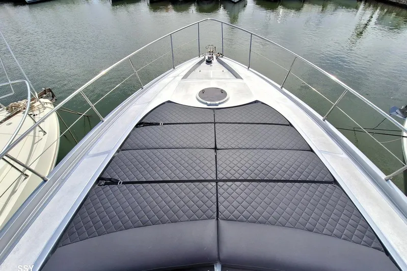 Domale Yacht Photos Pics 2009 Pershing 56 yacht bow with quilted sun pads, docked in calm waters.