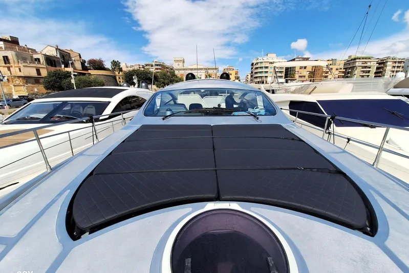 Domale Yacht Photos Pics 2009 Pershing 56 yacht docked in a marina, surrounded by buildings and clear skies.