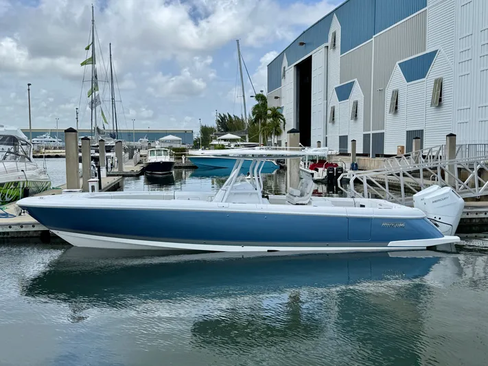  Yacht Photos Pics 2025 Intrepid 345 Nomad FE boat docked at marina, blue and white design.