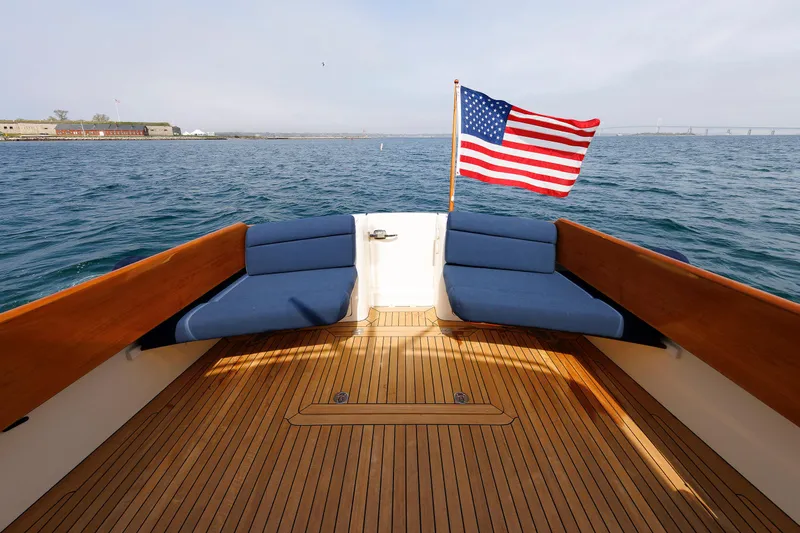 Ruckus Yacht Photos Pics Hinckley Talaria 44 MY 2009 yacht deck with American flag, blue cushions, and wooden flooring.