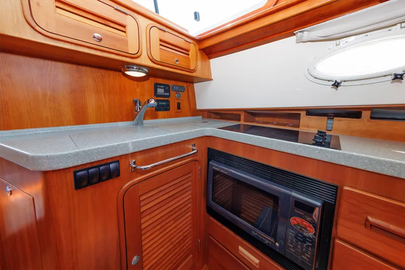 Ruckus Yacht Photos Pics Hinckley Talaria 44 MY 2009 yacht kitchen with wooden cabinetry, sink, and microwave.