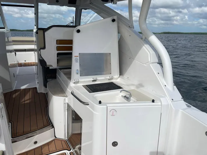 Lady B Yacht Photos Pics 2019 Pursuit 365 Dual Console boat interior with kitchenette and seating, on open water.