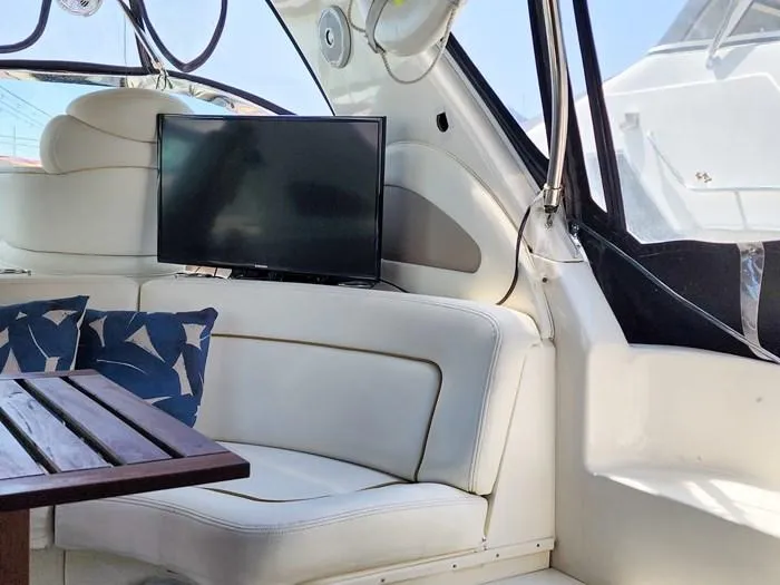  Yacht Photos Pics Interior of 1999 Sea Ray 460 Sundancer with TV, white seating, and wooden table.