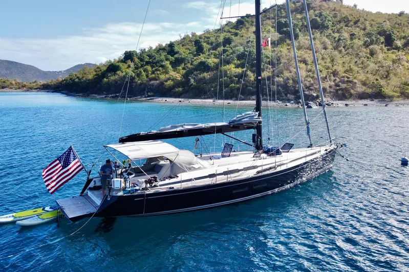Nehalennia Yacht Photos Pics Sailing yacht Nautor Swan 54 (2018) anchored in clear blue waters near a lush coastline.