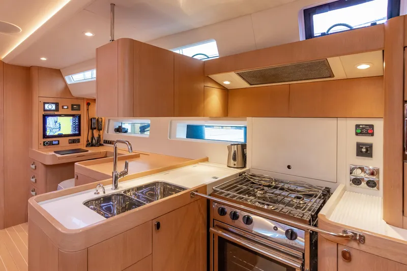 Nehalennia Yacht Photos Pics Modern kitchen interior of 2018 Nautor Swan 54 yacht, featuring sleek wood cabinetry and stainless steel appliances.