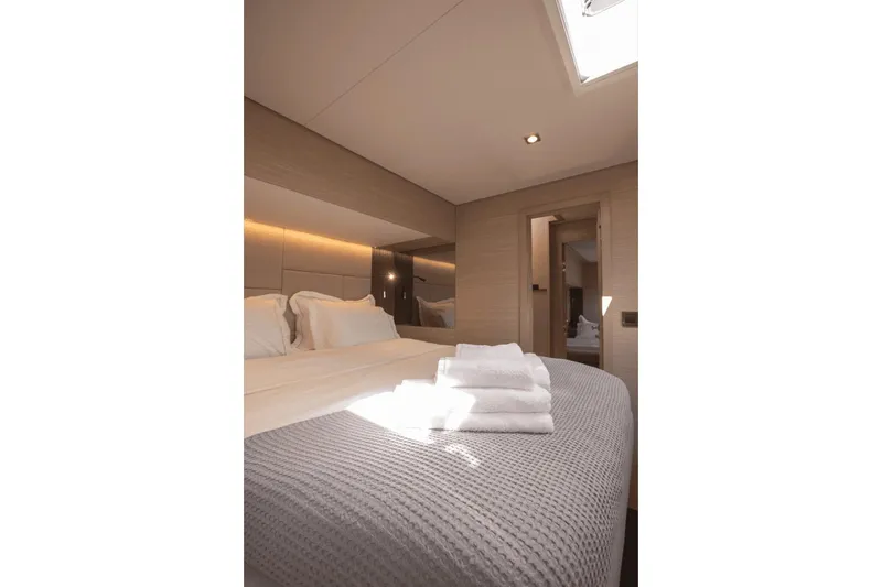  Yacht Photos Pics Luxurious bedroom interior of 2025 Lagoon 60 yacht with elegant bedding and soft lighting.