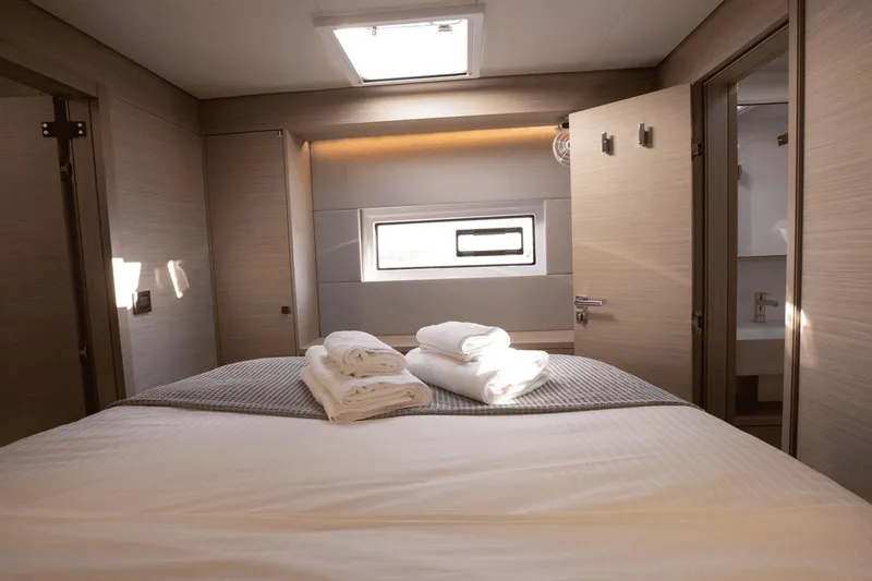  Yacht Photos Pics Luxurious bedroom interior of 2025 Lagoon 60 yacht with neatly arranged towels.