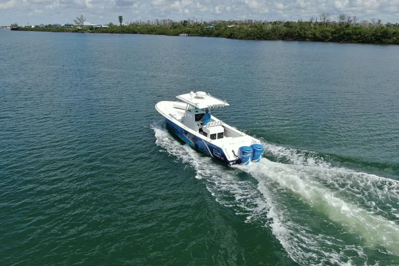  Yacht Photos Pics 2001 Regulator 32 Center Console boat cruising on a calm lake with lush shoreline.