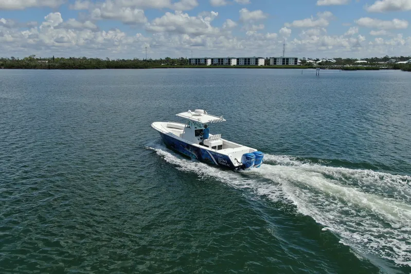  Yacht Photos Pics 2001 Regulator 32 Center Console boat cruising on a calm lake under a cloudy sky.