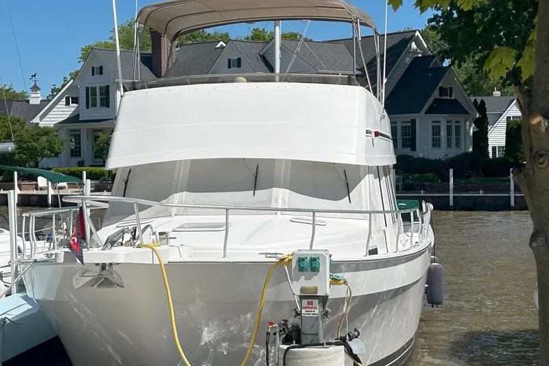 Knot Done Yet Yacht Photos Pics 2002 Mainship 430 Trawler docked near waterfront homes, featuring a spacious deck and canopy.