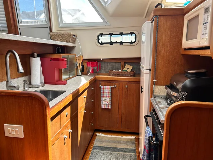 Knot Done Yet Yacht Photos Pics Cozy kitchen in 2002 Mainship 430 Trawler with wood cabinetry and modern appliances.