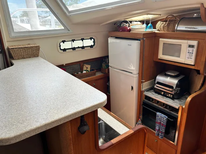 Knot Done Yet Yacht Photos Pics 2002 Mainship 430 Trawler kitchen with appliances, countertop, and storage baskets.