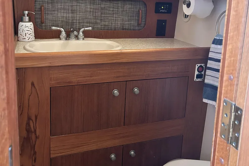 Knot Done Yet Yacht Photos Pics Wooden bathroom vanity in 2002 Mainship 430 Trawler with sink and storage cabinets.