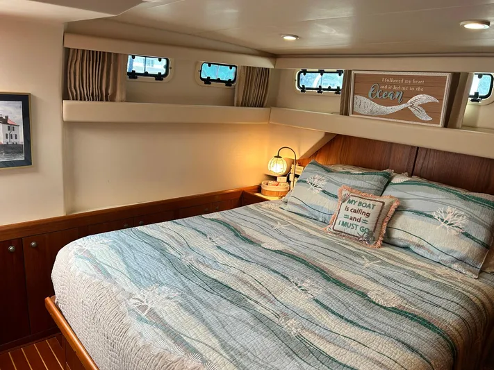 Knot Done Yet Yacht Photos Pics Cozy bedroom interior of 2002 Mainship 430 Trawler with nautical decor and soft lighting.