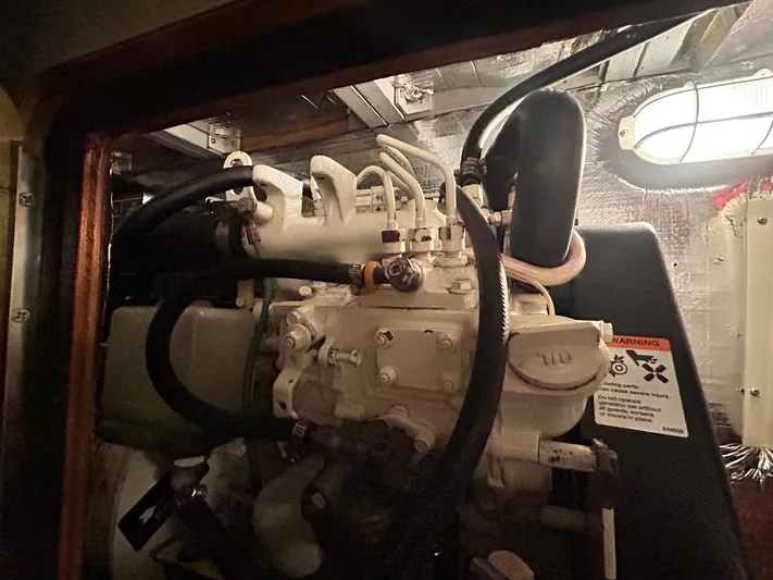 Knot Done Yet Yacht Photos Pics Engine room of a 2002 Mainship 430 Trawler with visible machinery and warning label.