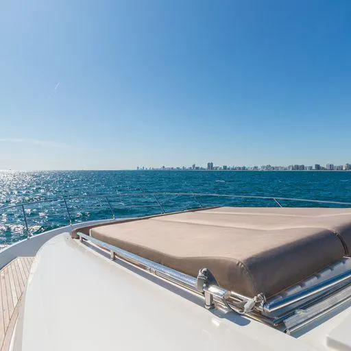 The Good Life Yacht Photos Pics Prestige 75 yacht cruising on open sea, 2015 model, clear blue sky and city skyline in background.