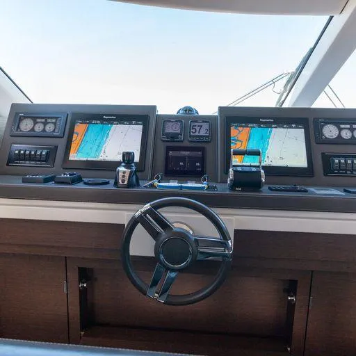 The Good Life Yacht Photos Pics Control panel of a 2015 Prestige 75 yacht with navigation screens and steering wheel.