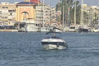 2007 Cranchi CSL 27 boat cruising in a marina with yachts and buildings in the background.