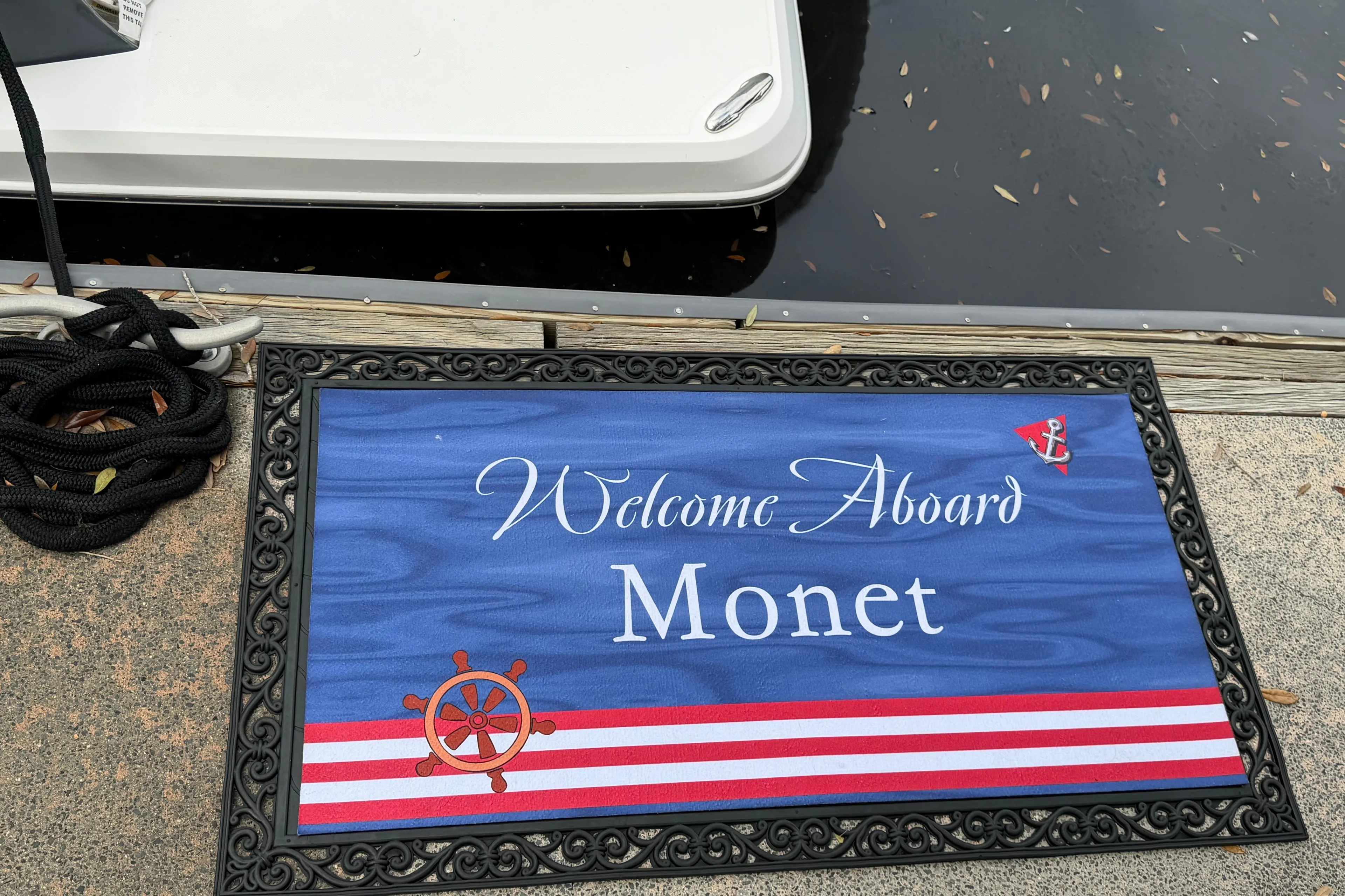 Welcome mat on dock beside 2021 Regal 36 XO boat, named Monet.