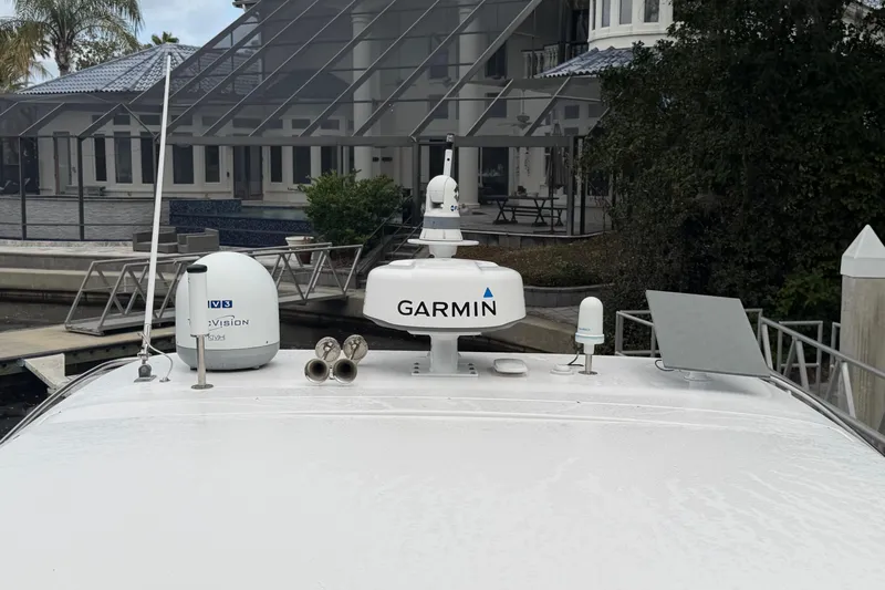 Monet Yacht Photos Pics 2021 Regal 36 XO boat with Garmin and TV3 antennas docked near a modern house.