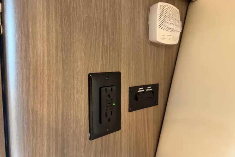 Monet Yacht Photos Pics 2021 Regal 36 XO interior with power outlet and antenna switch on wooden panel.