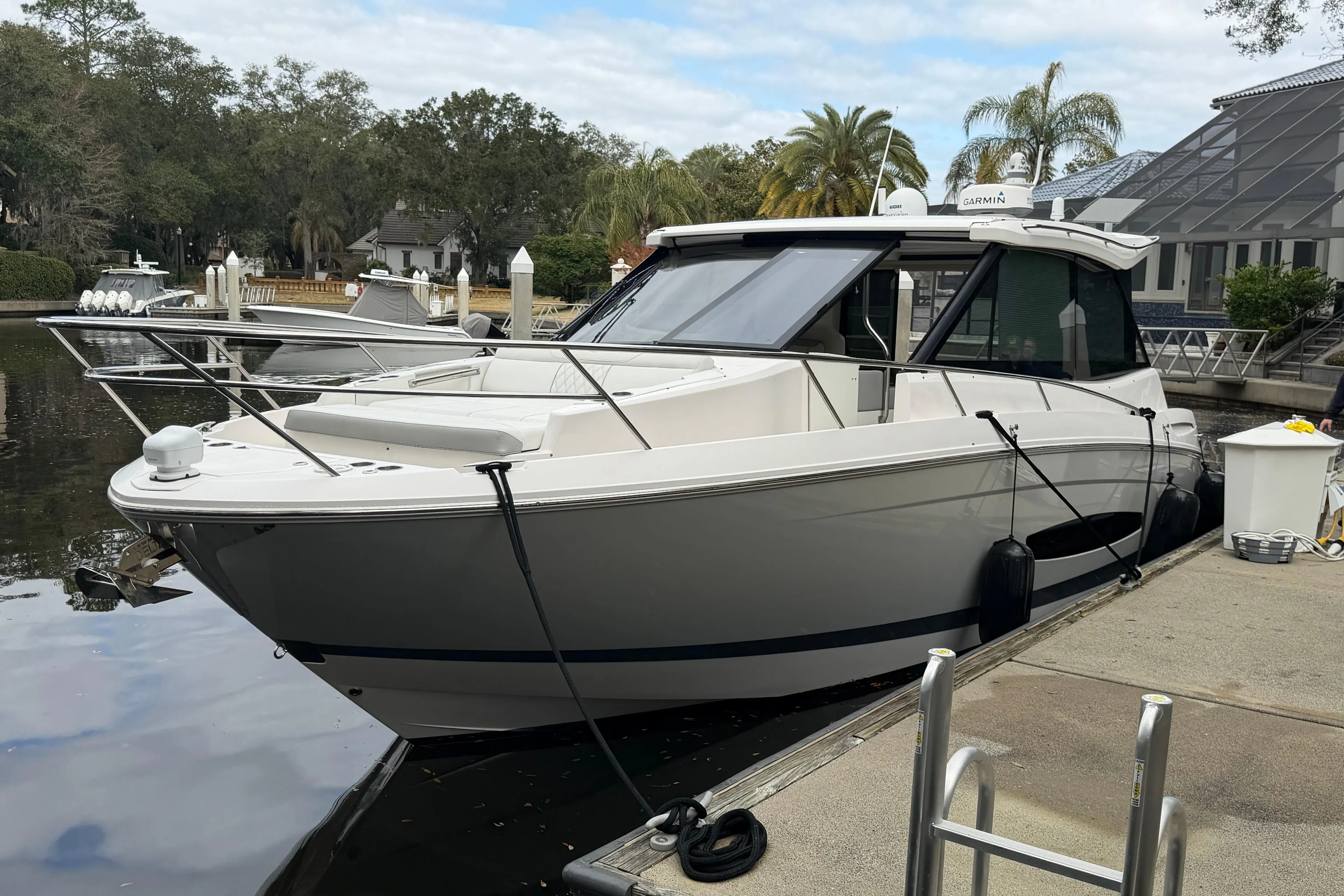 2021 Regal 36 XO boat docked by a scenic waterfront with trees and buildings.