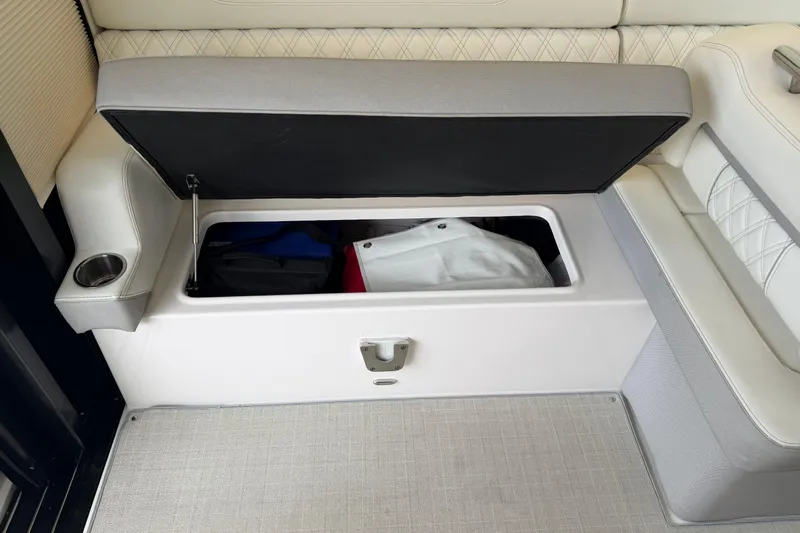 Monet Yacht Photos Pics 2021 Regal 36 XO boat seat storage compartment with open lid, revealing interior items.