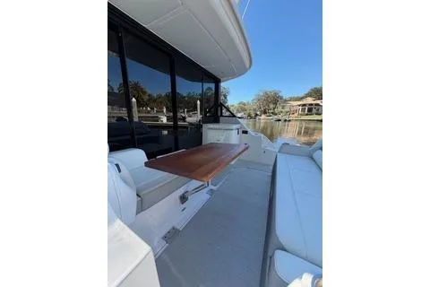 Monet Yacht Photos Pics 2021 Regal 36 XO yacht with sleek deck, wooden table, and comfortable seating.