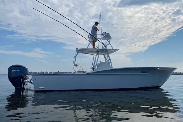  Yacht Photos Pics 2025 Custom Carolina Forbes boat on water, with person standing on deck, under cloudy sky.