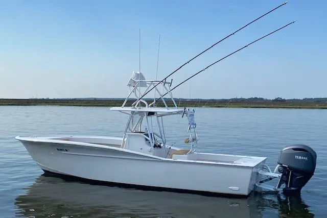  Yacht Photos Pics Custom Carolina Forbes 2025 boat with fishing rods on calm water, featuring Yamaha outboard motor.