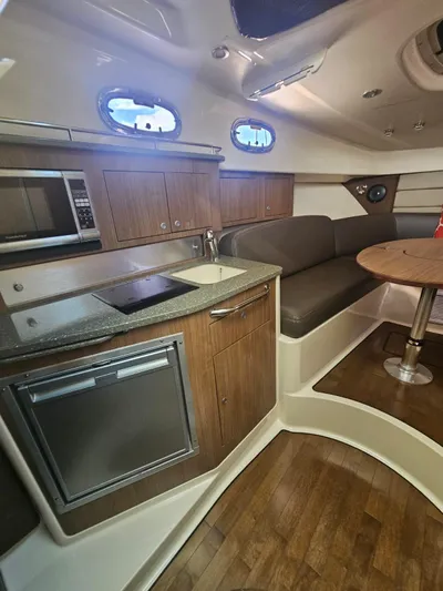  Yacht Photos Pics 2013 Boston Whaler 315 Conquest cabin with kitchenette, seating, and wood flooring.