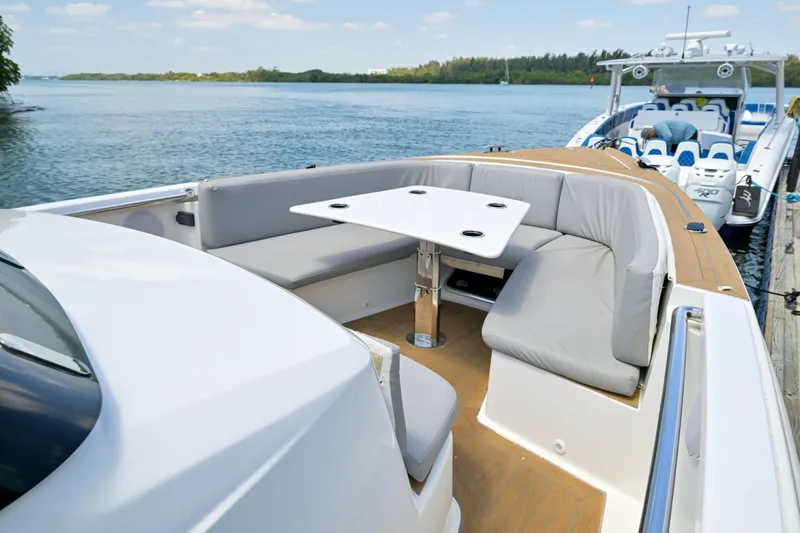  Yacht Photos Pics 2018 Fjord 36 Xpress boat with cushioned seating and table, docked by a scenic waterway.