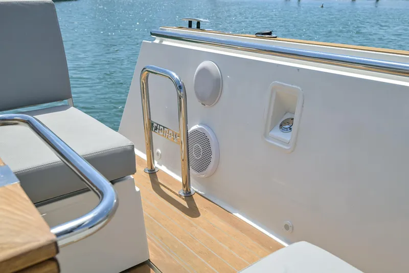  Yacht Photos Pics 2018 Fjord 36 Xpress boat deck with seating, speakers, and railing by the water.