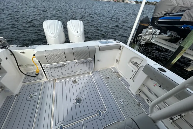  Yacht Photos Pics 2023 Pursuit S 288 Sport boat deck with dual engines, docked by the water.